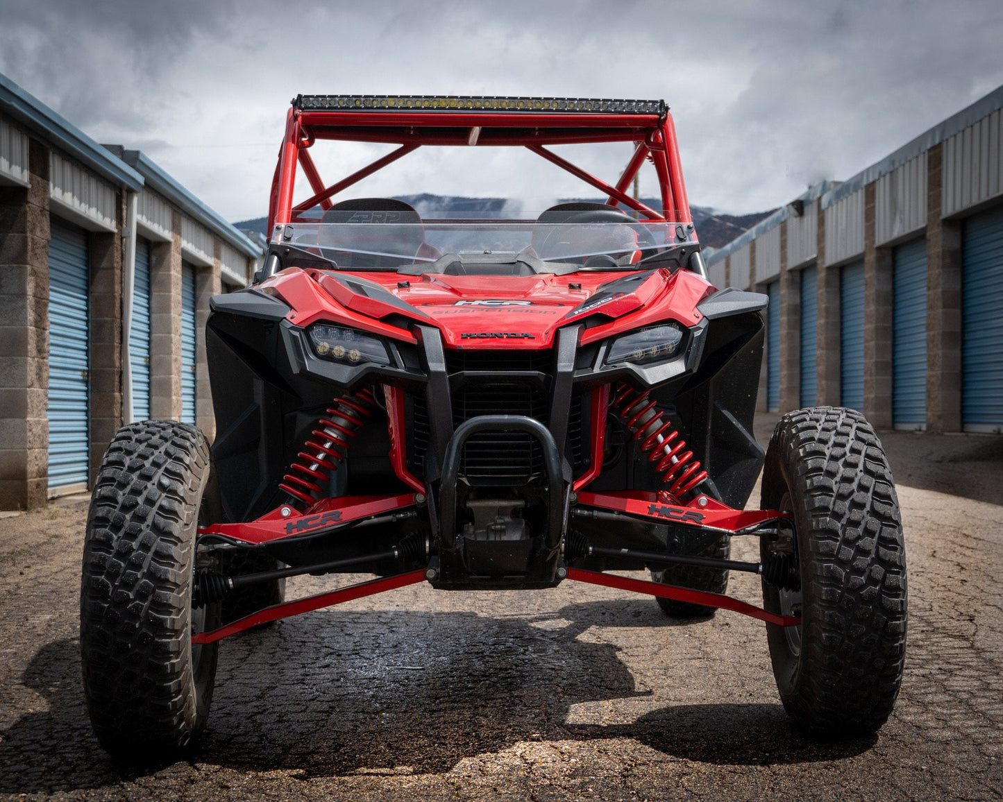 HCR RACING TAL-05400 HONDA TALON 1000R LONG TRAVEL SUSPENSION KIT showcased on a UTV in a storage area.